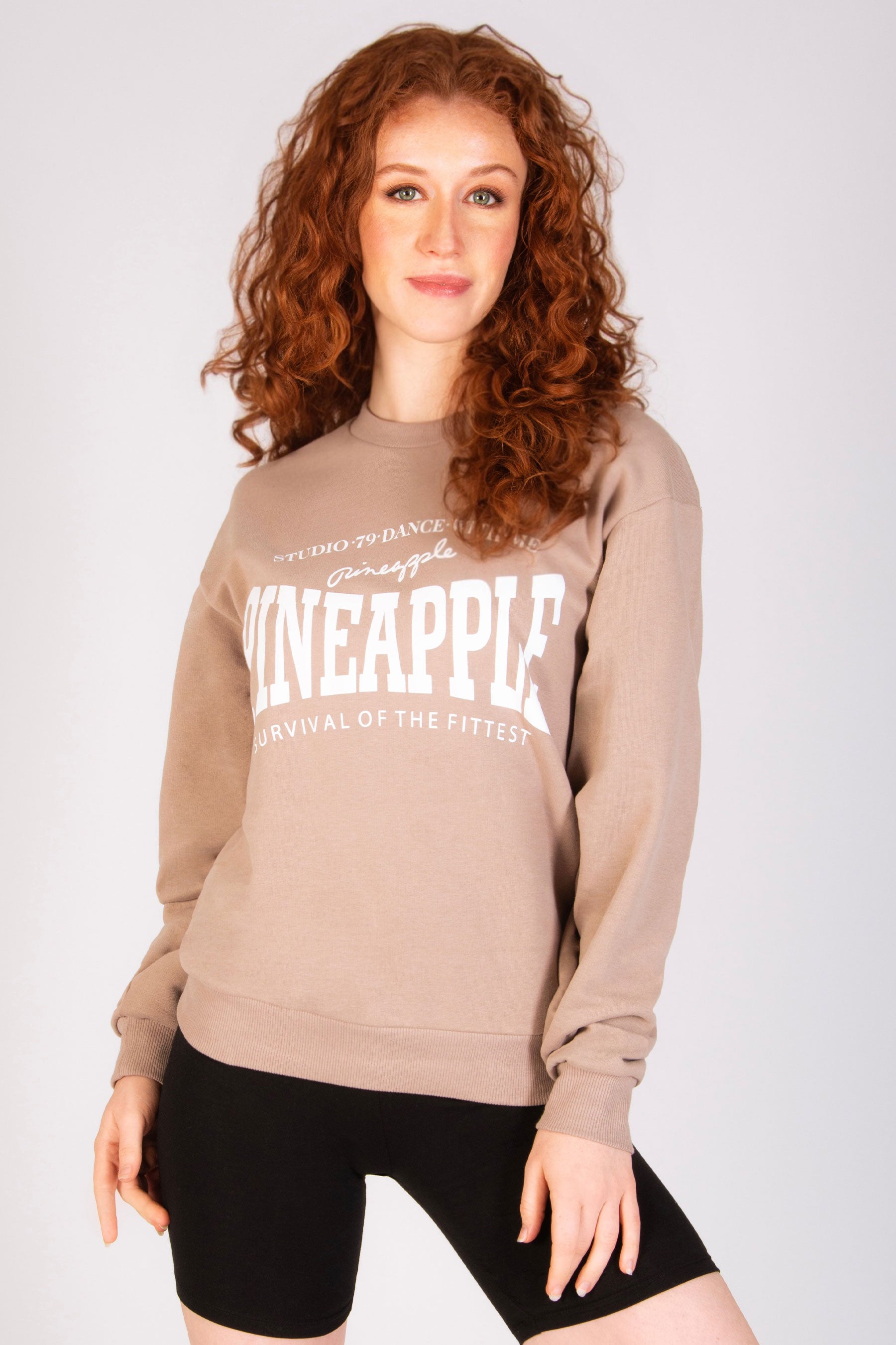 Women's light brown sweatshirt in oversized shape paired with cycling shorts.